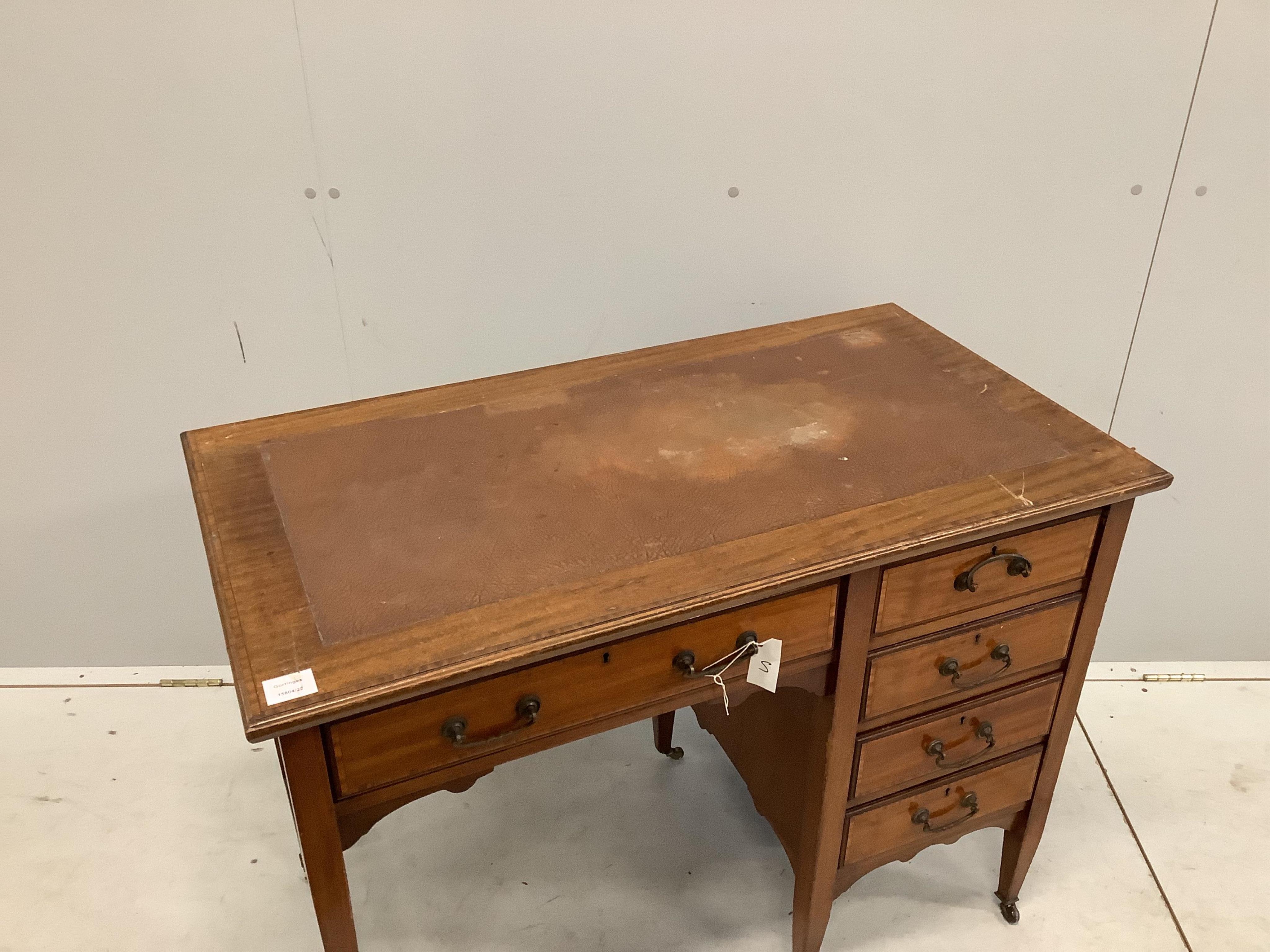 An Edwardian crossbanded mahogany kneehole desk, with moulded edge fitted one frieze drawer and four pedestal drawers, all with brass loop handles, set on square tapered legs with castors, width 99cm, depth 53cm, height